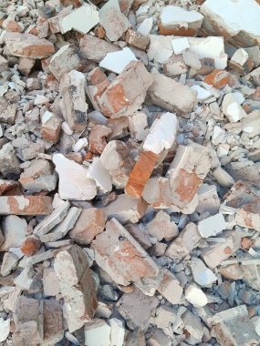 Kırık kırmızı tuğlalar ve beton parçaları. Yıkılmış bir binanın enkazı. İnşaat alanında büyük beton ve taş atığı var.