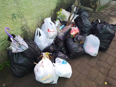 Bandung, Endonezya - 11 Nisan 2025: Kaldırımda plastik poşetlerle çöp yığını