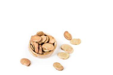Fava fasulyeleri seramik bir kasenin etrafına saçılmış beyaz yukarıdan aşağıya doğru izole edilmiş.