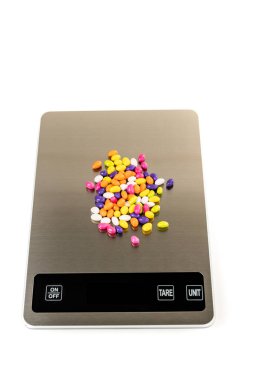 Fennel seed candy on a scale isolated over white top down