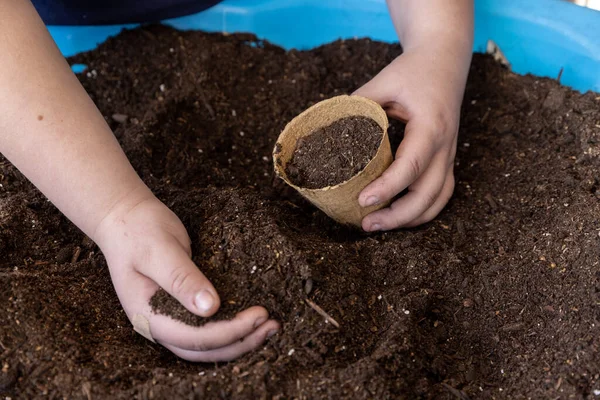 Scooping potting soil into a container from a pool full of dirt