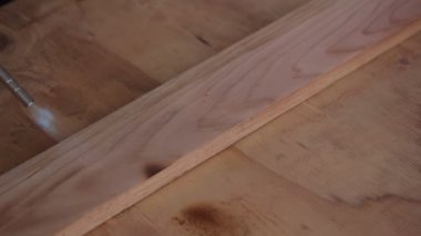 Propan meşalesi mavi alevi yavaş çekimde bir tahtanın yüzeyinden geçiyor.