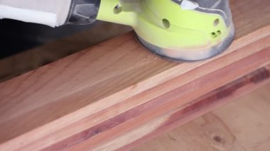 Yörünge zımpara makinesi yavaşça yüzeyden geçiyor. Geriye talaş tozu bırakıyor. Yavaş çekim.