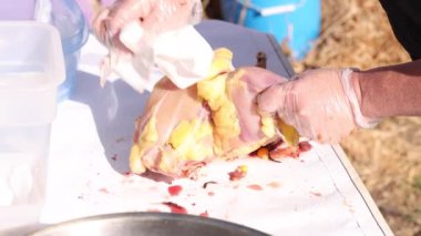 Eldivenli eller, kağıt havluyla tavuk leşinden tüy kalıntılarını temizliyor.