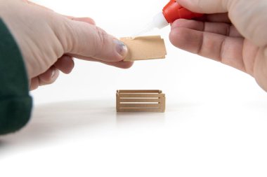 Kırık elma kutusunu tamir eden eller tabanına yapıştırıcı sürüyor.