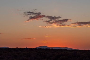 Yazın dumandan etkilenen orman yangınları sırasında karanlık ufukta turuncu pembe gün batımı