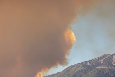 Nevada 'da büyük turuncu bir duman sütunu üzerinde iki küçük uçak yangınlarla savaşıyor.