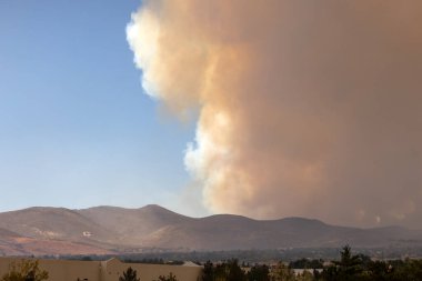Galena G, Reno 'da bir tepenin yamacında, arkasında kocaman turuncu bir duman bulutu yükseliyor.