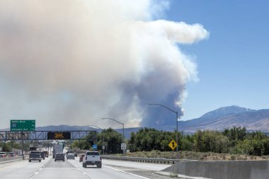 Plume of wildfire smoke from Davis fire south of Reno in the background of a freeway sign warning of fire danger clipart