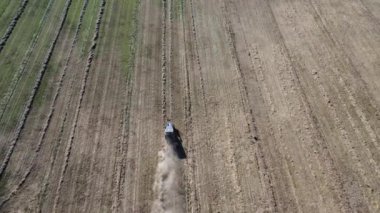 Traktör yukarıdan aşağı görünüyor tozlu bir tarlada samanları sıralara ayırıyor