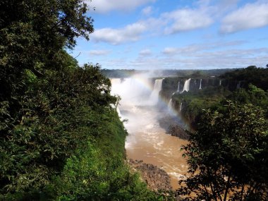 Güçlü şelalelerin ve Iguazu 'daki yemyeşil yeşilliklerin göz kamaştırıcı manzarası, canlı bir gökkuşağı ile.