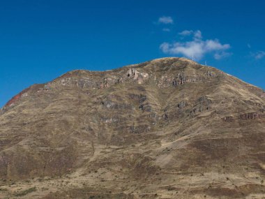 Kuru altın çimenler ve berrak mavi gökyüzü ile güneşli bir dağ engebeli doğal bir manzaranın güzelliğini gözler önüne seriyor..