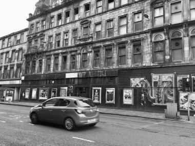 Glasgow, İngiltere 12 Ağustos 2017: Glasgow, İngiltere 'de sokak köşesinden geçen bir arabanın monokrom çekimi, burada bir bina duvarı, şehrin kentsel yaratıcılığını gözler önüne seren çarpıcı graffiti sanatıyla süslenmiş..