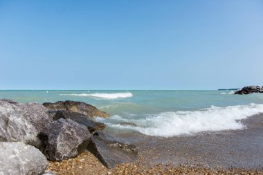 Michigan gölü üstünlüğü, büyük göller, petoski taşları, açık mavi gökyüzü ve kayalık plajı olan berrak mavi su. Dalgalar.