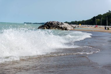 Chicago, IL, ABD - 27 Ağustos 2023: Michigan Gölü yakınlarındaki sahil. Göl ve sahil kenarında büyük bir taş yığını. İnsanlar sahilde dinleniyor..