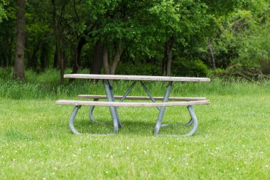 Park pikniği masasında dinlenme, dışarıda dinlenme. Eğlence alanındaki yeşil çimlerin üzerindeki banklar ve masalar.