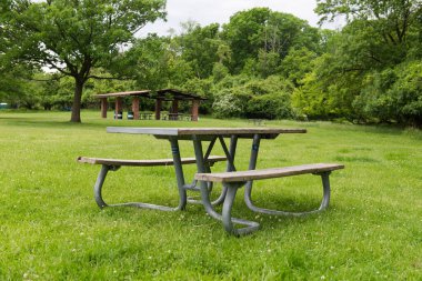 Park pikniği masasında dinlenme, dışarıda dinlenme. Eğlence alanındaki yeşil çimlerin üzerindeki banklar ve masalar.