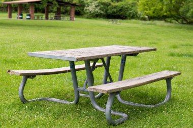Park pikniği masasında dinlenme, dışarıda dinlenme. Eğlence alanındaki yeşil çimlerin üzerindeki banklar ve masalar.