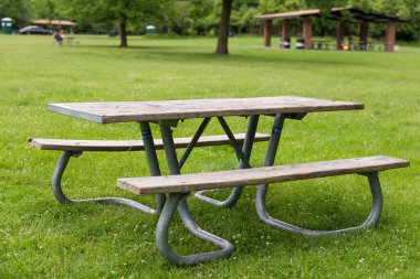 Park pikniği masasında dinlenme, dışarıda dinlenme. Eğlence alanındaki yeşil çimlerin üzerindeki banklar ve masalar.