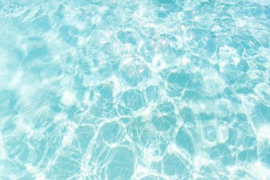 Temiz turkuaz suyun parlak ve ferahlatıcı görüntüsü. Güneş yansımaları ve ışık dalgaları. Yaz arkaplanı, spa teması ya da tatil konsepti kadar mükemmel..