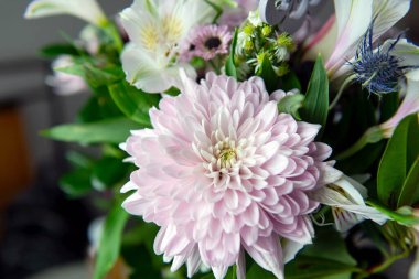 Pembe kasımpatı, beyaz zambaklar, güller, asterlar ve diğer mevsimlik çiçeklerden oluşan canlı bir çiçek buketi. Romantik, ilkbahar veya kutlama temaları için mükemmel. Kapalı alanda doğal ışıkta yakalandılar..