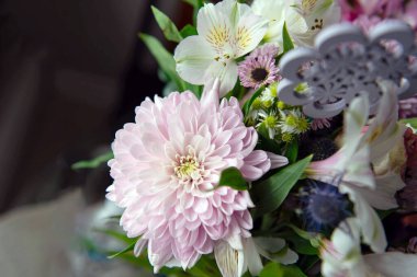 Pembe kasımpatı, beyaz zambaklar, güller, asterlar ve diğer mevsimlik çiçeklerden oluşan canlı bir çiçek buketi. Romantik, ilkbahar veya kutlama temaları için mükemmel. Kapalı alanda doğal ışıkta yakalandılar..