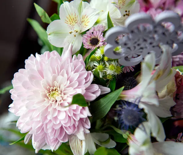 Pembe kasımpatı, beyaz zambaklar, güller, asterlar ve diğer mevsimlik çiçeklerden oluşan canlı bir çiçek buketi. Romantik, ilkbahar veya kutlama temaları için mükemmel. Kapalı alanda doğal ışıkta yakalandılar..