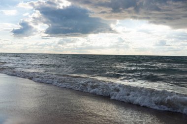 Michigan Gölü 'nün üzerinde kara bulutlar dalgalar kıyıya vururken. Su dokusu, yansıması ve fırtınalı gökyüzü manzaralı. Huzurlu ama güçlü ruh hali.