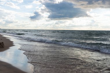 Michigan Gölü kıyılarında yumuşak dalgalar ve dramatik bulutlar var. Huzurlu doğal deniz manzarası, doğa, seyahat ve rahatlama temaları için birebirdir. Bir yaz öğleden sonra çekilmiş..
