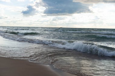 Uçan bir kuşla dramatik gökyüzünün altında dalgalar sahile çarpıyor. Bulutlu gökyüzü ve uçan bir kuşla sahilde vahşi dalgalar. Doğal deniz manzarası, doğa, seyahat ve özgürlük temaları için mükemmel. Michigan Gölü 'nde yakalandı..