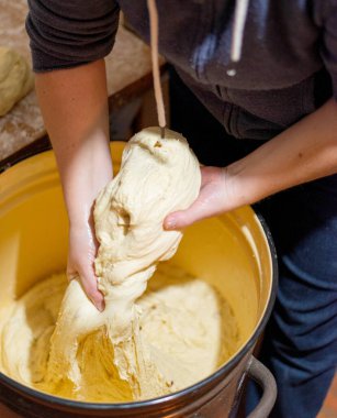 Büyük kahverengi bir kasede taze hamur yoğuran kadın ellerine yakın plan. Geleneksel ekmek hazırlama süreci. Sıfırdan ev yapımı pişirme.