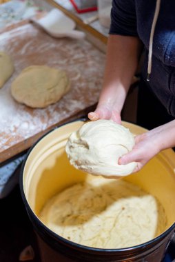 Büyük kahverengi bir kasede taze hamur yoğuran kadın ellerine yakın plan. Geleneksel ekmek hazırlama süreci. Sıfırdan ev yapımı pişirme.