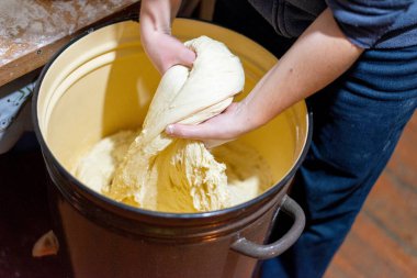 Büyük kahverengi bir kasede taze hamur yoğuran kadın ellerine yakın plan. Geleneksel ekmek hazırlama süreci. Sıfırdan ev yapımı pişirme.