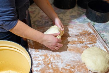 Köy mutfağında ekmek hamuru şekillendiren kadın ellerinin yakın çekimi. Masanın üzerinde siyah pişirme şekilleri olan ev yapımı pişirme işlemi. Geleneksel sıfırdan ekmek pişirme.