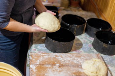 Köy mutfağında ekmek hamuru şekillendiren kadın ellerinin yakın çekimi. Masanın üzerinde siyah pişirme şekilleri olan ev yapımı pişirme işlemi. Geleneksel sıfırdan ekmek pişirme.