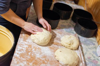 Köy mutfağında ekmek hamuru şekillendiren kadın ellerinin yakın çekimi. Masanın üzerinde siyah pişirme şekilleri olan ev yapımı pişirme işlemi. Geleneksel sıfırdan ekmek pişirme.