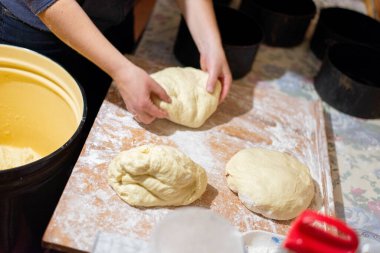 Köy mutfağında ekmek hamuru şekillendiren kadın ellerinin yakın çekimi. Masanın üzerinde siyah pişirme şekilleri olan ev yapımı pişirme işlemi. Geleneksel sıfırdan ekmek pişirme.