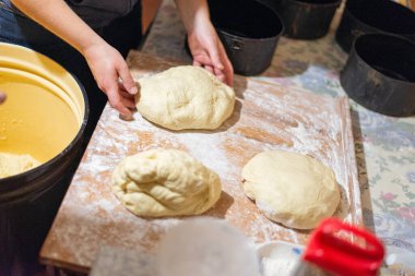 Köy mutfağında ekmek hamuru şekillendiren kadın ellerinin yakın çekimi. Masanın üzerinde siyah pişirme şekilleri olan ev yapımı pişirme işlemi. Geleneksel sıfırdan ekmek pişirme.