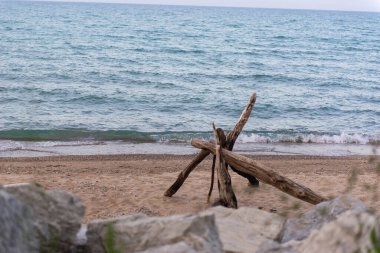 Su kenarında kumlu sahilde uzanan doğal akıntı dalgaları kıyıya vuruyor. Manzaralı deniz manzarası ahşap dokuya ve mavi su arka planına sahip..