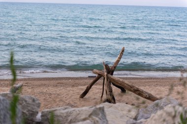 Su kenarında kumlu sahilde uzanan doğal akıntı dalgaları kıyıya vuruyor. Manzaralı deniz manzarası ahşap dokuya ve mavi su arka planına sahip..