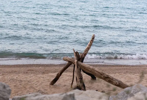 Su kenarında kumlu sahilde uzanan doğal akıntı dalgaları kıyıya vuruyor. Manzaralı deniz manzarası ahşap dokuya ve mavi su arka planına sahip..