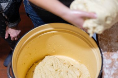 Büyük kaseden çiğ maya hamuru ve kuru üzümlü kuru üzüm alarak ellerini yaklaştır. Geleneksel ev yapımı ekmek hazırlama, kırsal yemek pişirme ve pişirme süreci.