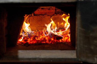 Parlak odun ve içinde ev yapımı ekmek pişirme ve geleneksel yemek pişirme için kullanılan parlak alevlerle taşralı bir tuğla fırını kapatın..