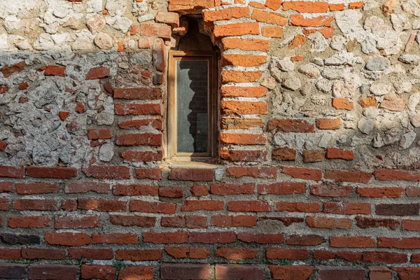 The stone wall and small window of old vintage house captured in old city of Alanya. Texture of stone building wall.