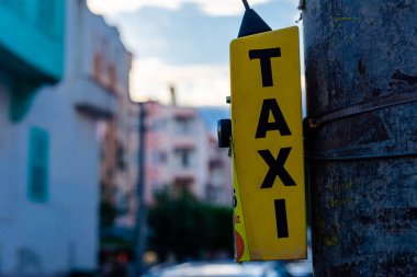 Button to call a taxi in the Turkish city of Alanya. Evening photo of a yellow block with a button and the inscription TAXI. A taxi call point hangs on a pole in the street.