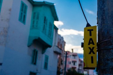 Button to call a taxi in the Turkish city of Alanya. Evening photo of a yellow block with a button and the inscription TAXI. A taxi call point hangs on a pole in the street.