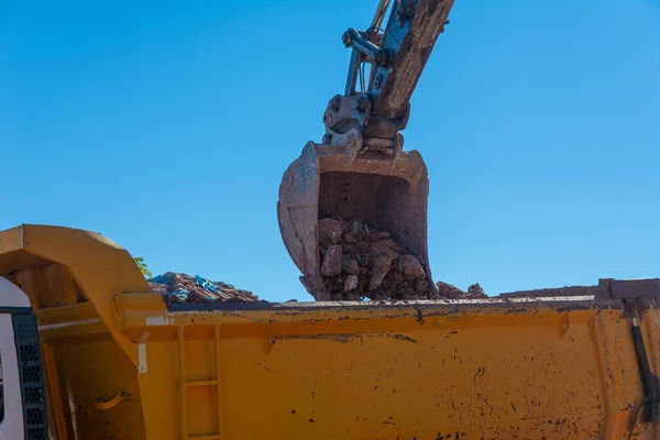 Heavy machinery works at the construction site. Clearing rocky soil for construction in Turkey. Excavator loading rocks into a truck.