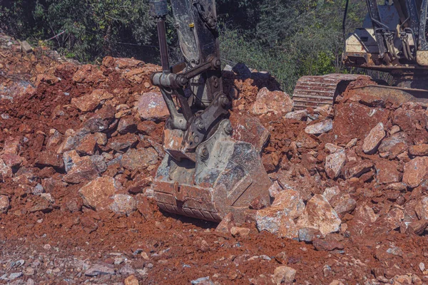 Heavy machinery works at the construction site. Clearing rocky soil for construction in Turkey. The excavator crushes the rock.