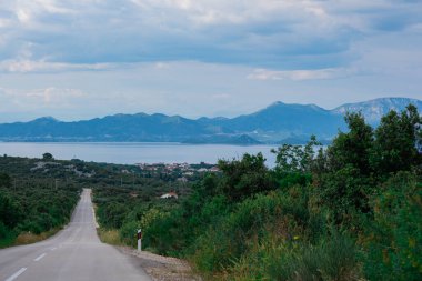 Hırvatistan 'da bir adanın kırsal kesiminde bir yol. Hareketin bulanık etkisi, deniz ve dağlar uzaktan görülebilir..