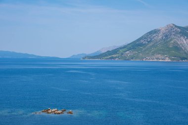 Güzel bir göl manzarası, çam ormanı ve vahşi plaj manzarası. Adriyatik Denizi 'nin muhteşem turkuaz suları, arka planda dağlar görülebilir..